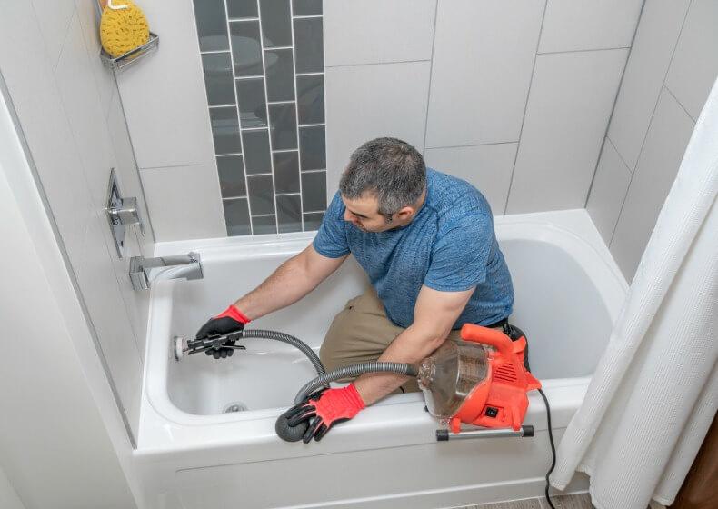 a clogged drain being cleared with a handheld auger in Greene